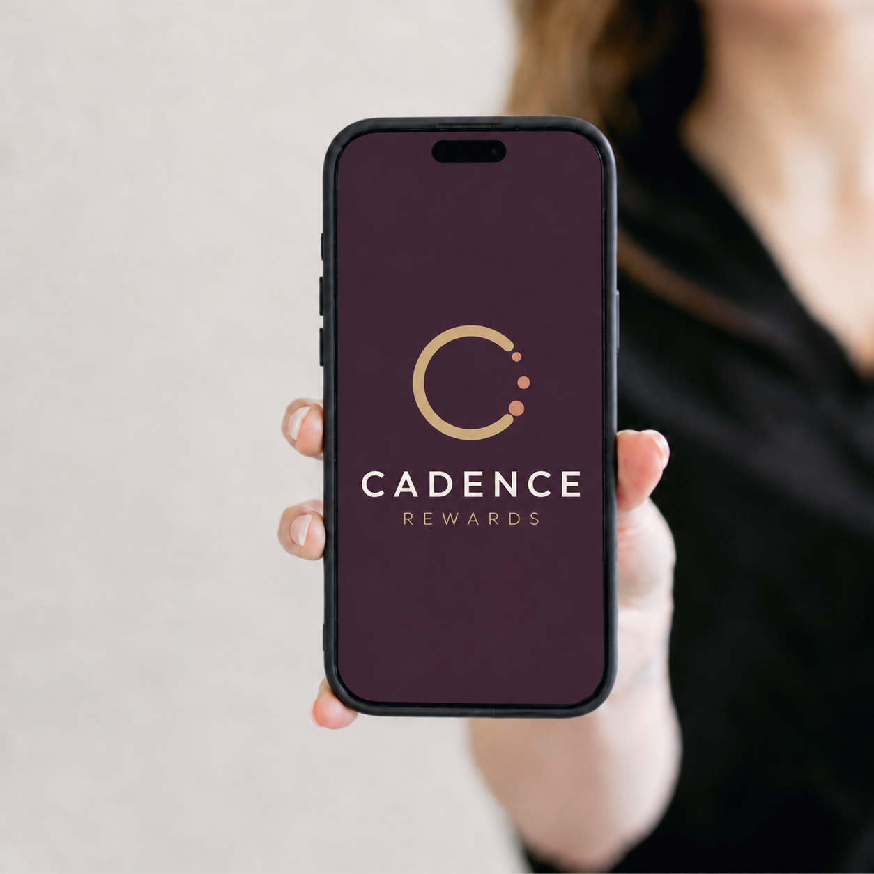 A person holds a phone showing the Cadence Rewards app